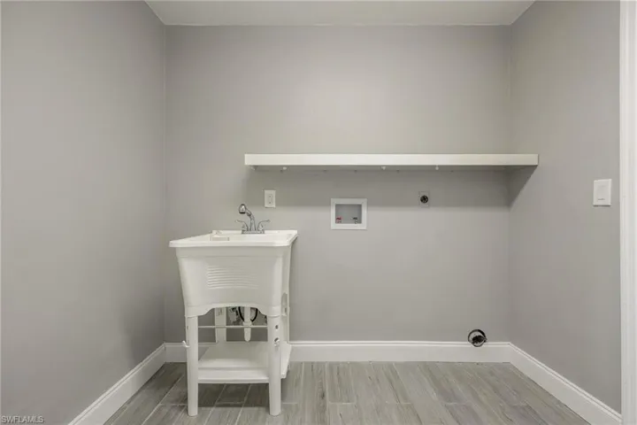Laundry room featuring washer hookup, wood finished floors, hookup for an electric dryer, laundry area, and baseboards