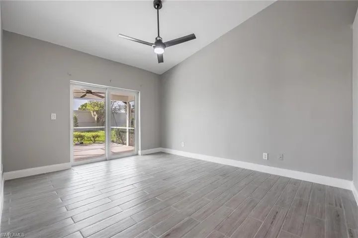 Unfurnished room with a ceiling fan, baseboards, lofted ceiling, and wood finished floors