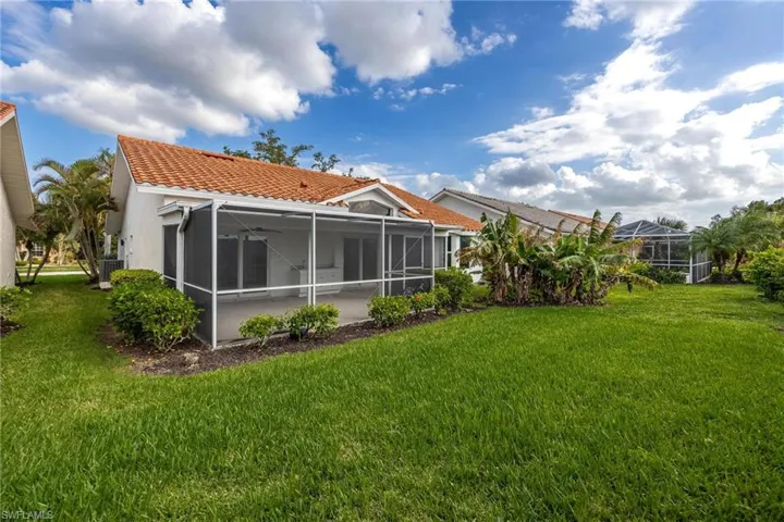 Back of house featuring stucco siding, a tile roof, cooling unit, and a yard