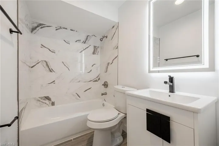 Full bathroom with toilet, shower / tub combination, vanity, and wood finished floors