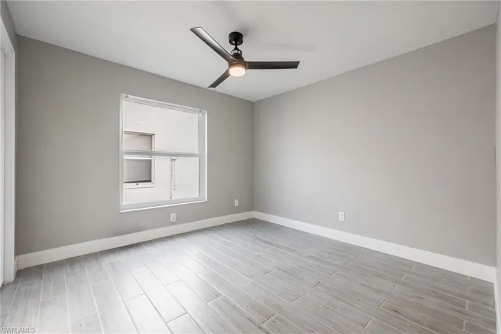 Unfurnished room with baseboards, ceiling fan, and light wood-style flooring