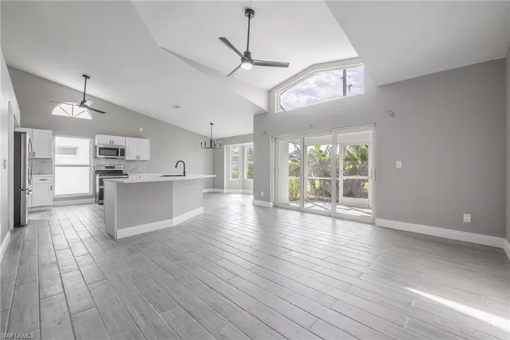 Kitchen with open floor plan, light wood-style flooring, appliances with stainless steel finishes, and ceiling fan