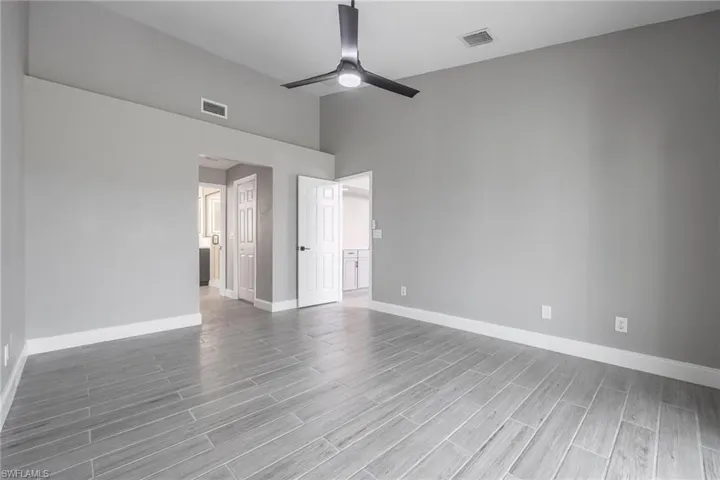 Empty room with baseboards, visible vents, ceiling fan, and wood finish floors