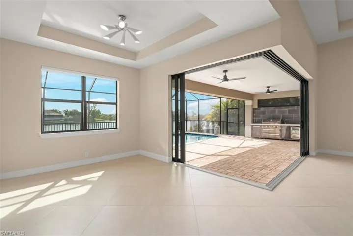 Unfurnished living room with ceiling fan, a tray ceiling, and light tile patterned floors