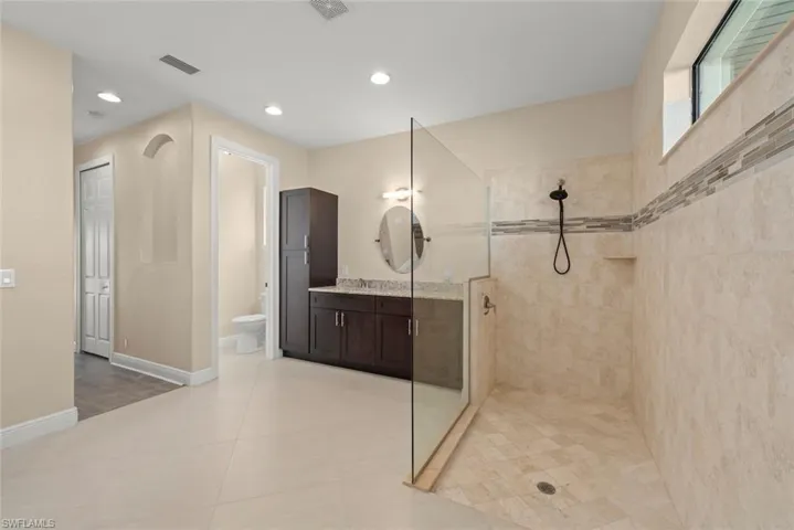 Bathroom with vanity, tile patterned flooring, toilet, and tiled shower