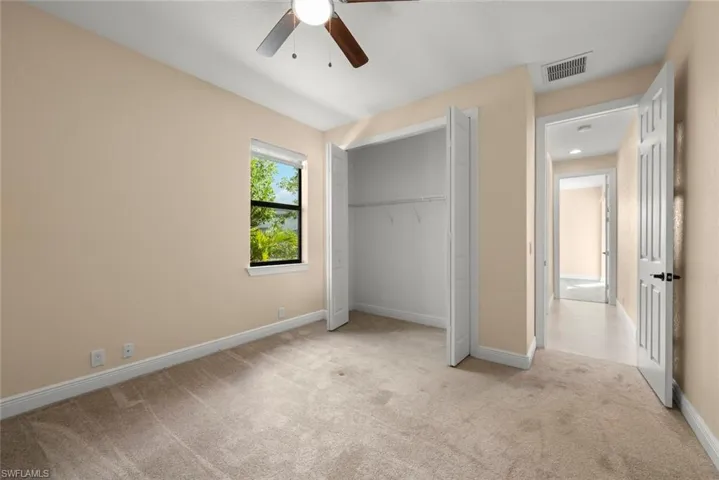 Unfurnished bedroom with light colored carpet, a closet, and ceiling fan