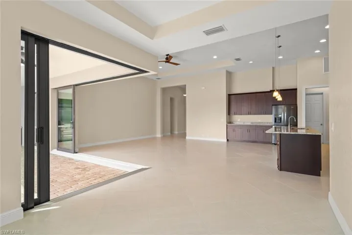 Unfurnished living room with light tile patterned floors, a raised ceiling, ceiling fan, and a high ceiling
