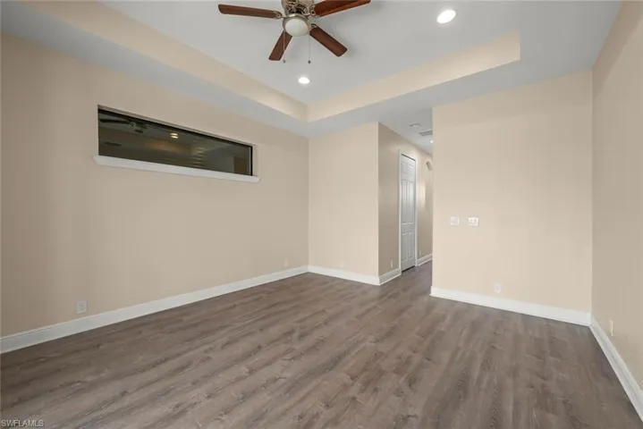 Unfurnished room with a raised ceiling, hardwood / wood-style floors, and ceiling fan