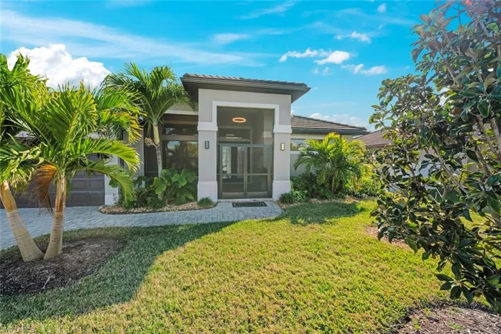 View of exterior entry featuring a yard and a garage