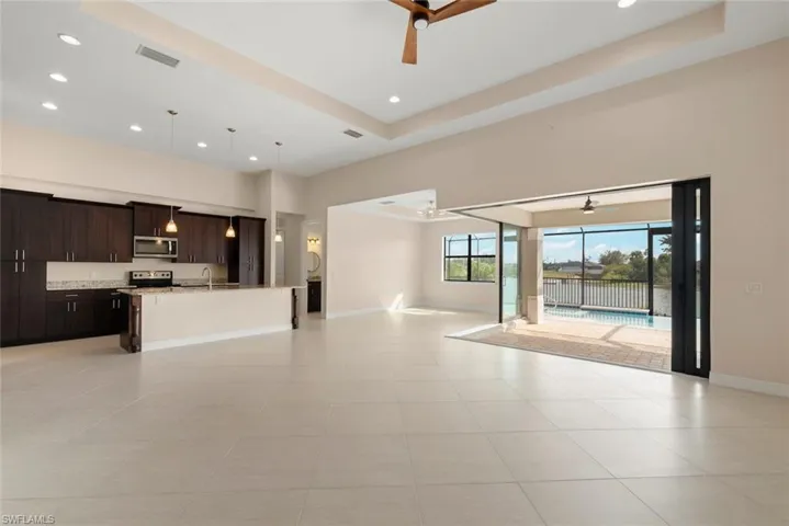 Kitchen featuring ceiling fan, appliances with stainless steel finishes, dark brown cabinetry, and decorative light fixtures