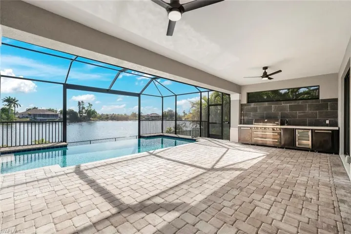 View of swimming pool with a water view and ceiling fan
