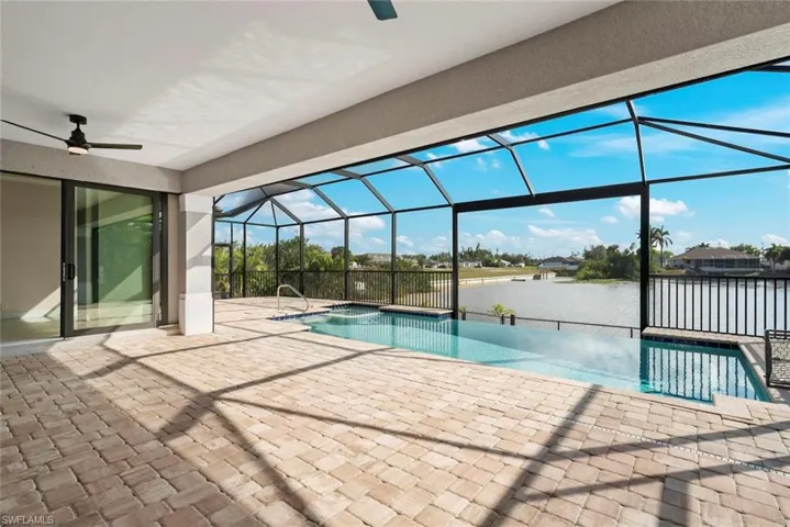 View of swimming pool with a lanai, a patio, ceiling fan, and a water view