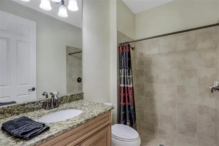 Full bath with vanity, a tile shower, and a chandelier