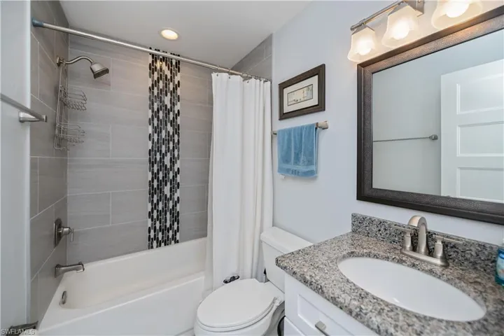 Bathroom featuring vanity, shower / bath combination with curtain, and recessed lighting