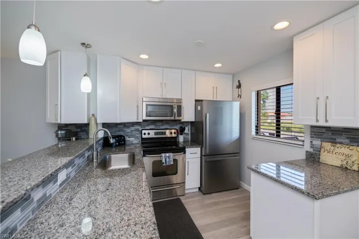 Kitchen with decorative backsplash, stainless steel appliances, white cabinets, and recessed lighting