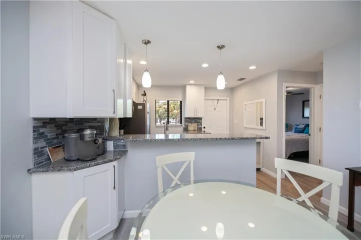 Kitchen featuring backsplash, white cabinetry, recessed lighting, dark stone countertops, and a peninsula