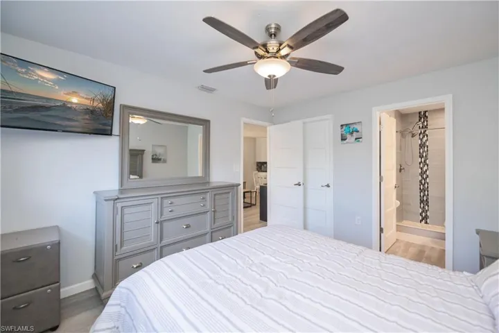 Bedroom with wood finished floors, a ceiling fan, and connected bathroom