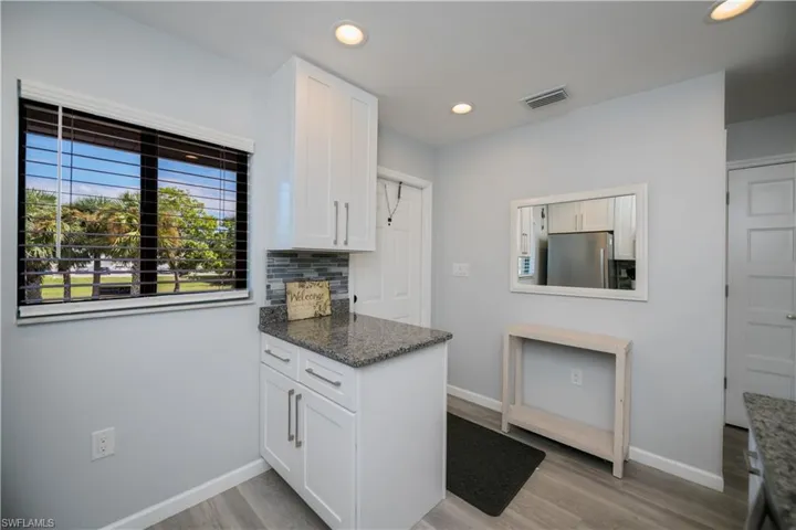 Kitchen with backsplash, white cabinetry, freestanding refrigerator, light wood-style flooring, and recessed lighting