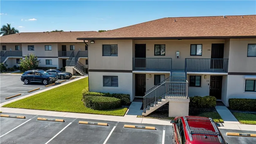 View of property featuring stairway and uncovered parking