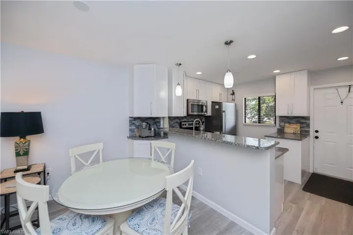 Kitchen with white cabinets, dark stone countertops, tasteful backsplash, and recessed lighting