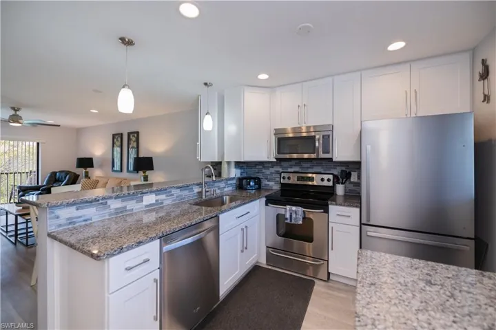 Kitchen with appliances with stainless steel finishes, white cabinetry, backsplash, open floor plan, and recessed lighting