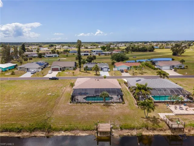 Waterfront property featuring a screened-in swimming pool, a private dock, and an expansive lawn