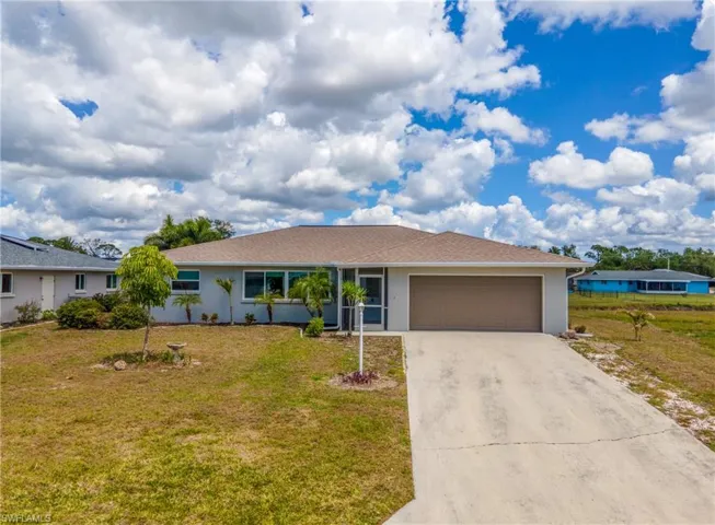 Ranch-style residence featuring a textured exterior, a brown shingle roof, and an attached two-car garage with a brown door