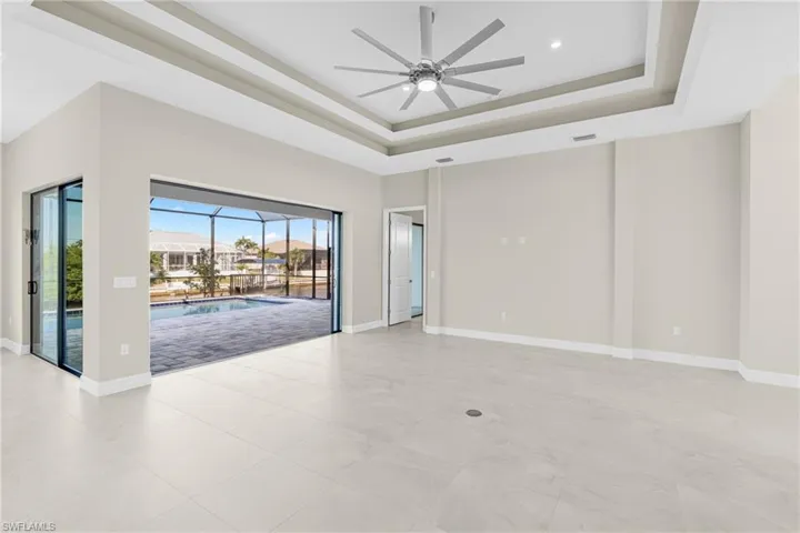Spare room with a sunroom, a tray ceiling, and ceiling fan