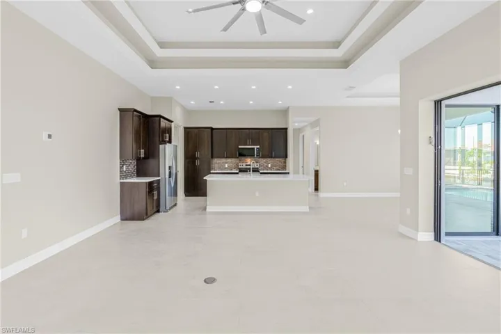 Unfurnished living room with a tray ceiling and a ceiling fan