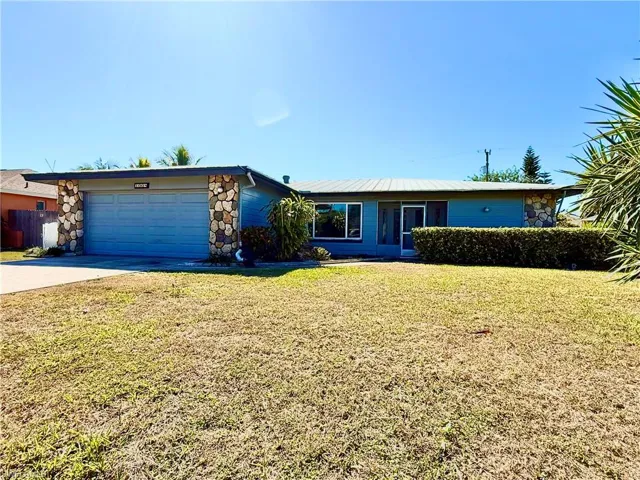 View of front of home with a front yard, concrete driveway, stone siding, and a garage