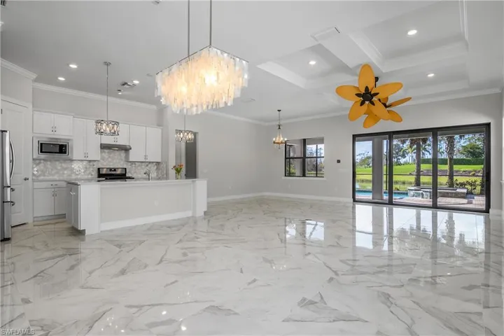 Kitchen featuring a kitchen island with sink, white cabinetry, decorative light fixtures, and appliances with stainless steel finishes