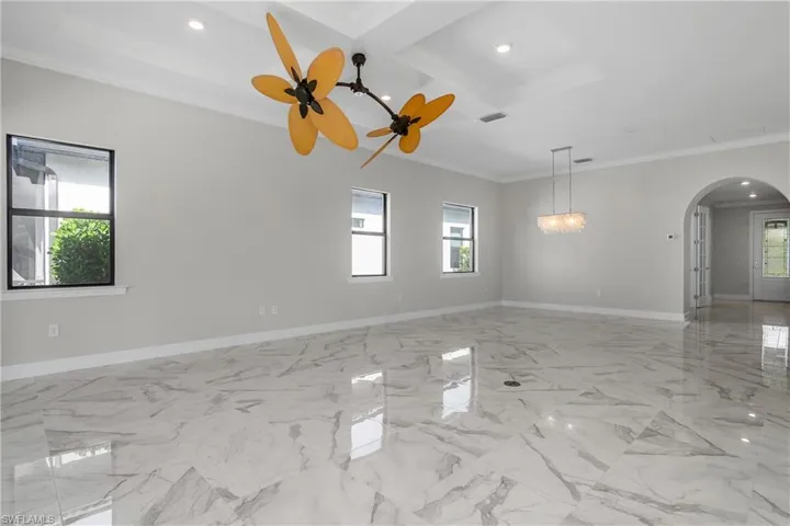 Great room with open living, dining, and kitchen features decorative fans, crown molding, tray ceilings, and spacious kitchen with lots of storage space.