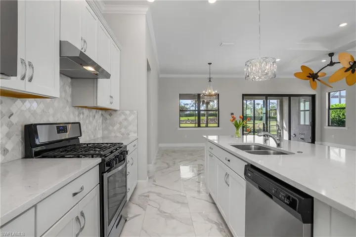 Kitchen includes white cabinetry, quartz countertops, natural gas stove, tile backsplash, walk-in pantry and crown molding.