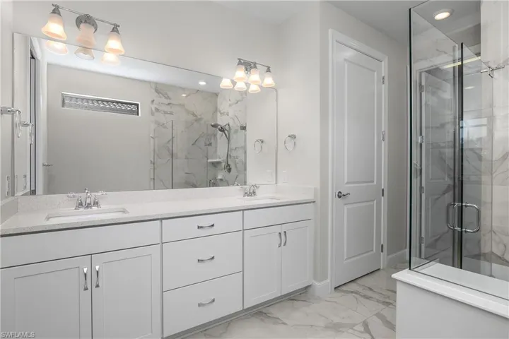 Owner bath with dual sinks, frameless glass walk-in shower, and walk-in closet.