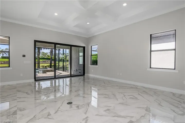 Freshly painted interior with great room featuring coffered ceiling, crown molding, a wealth of natural light, and beamed ceiling.