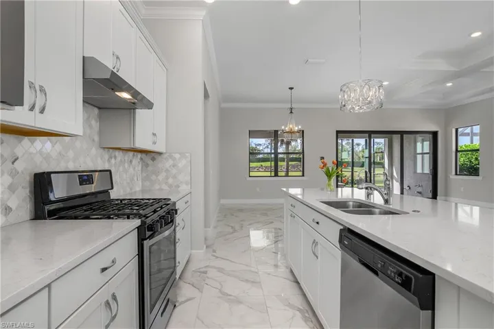 Kitchen includes white cabinetry, quartz countertops, natural gas stove, tile backsplash, walk-in pantry and crown molding.