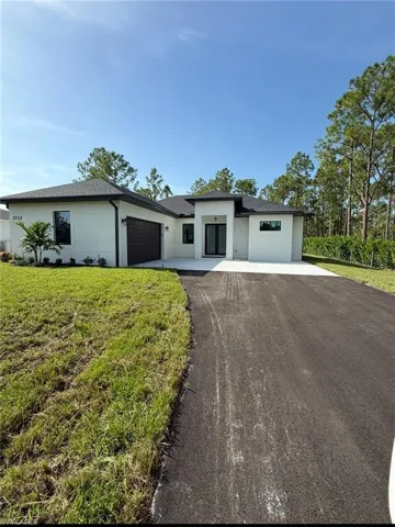 Prairie-style house featuring asphalt driveway, a garage, a front yard, roof with shingles, and stucco siding
