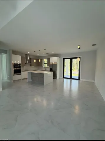 Unfurnished living room with light marble finish floors and recessed lighting