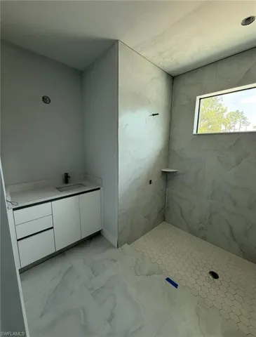 Full bath with vanity, marble look tiles, and tiled shower
