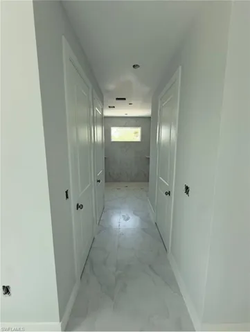 Hallway with light marble finish floors and baseboards