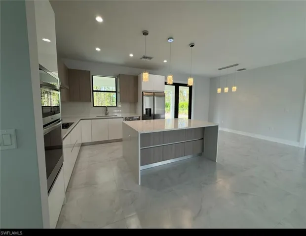 Kitchen with decorative light fixtures, light marble finish floors, recessed lighting, modern cabinets, and a center island