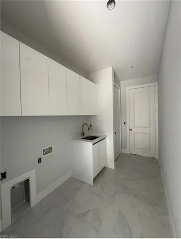 Washroom with cabinet space, light marble finish floors, and washer hookup