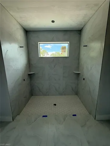Bathroom featuring marble look tile flooring and tiled shower