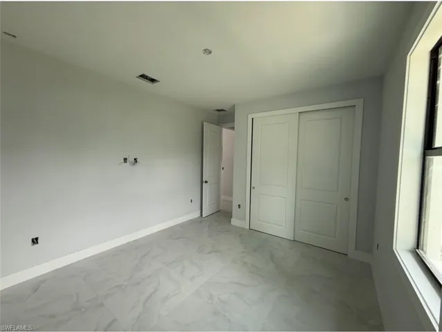 Unfurnished bedroom with light marble finish flooring and a closet