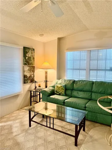 Carpeted living room featuring a textured ceiling and a ceiling fan
