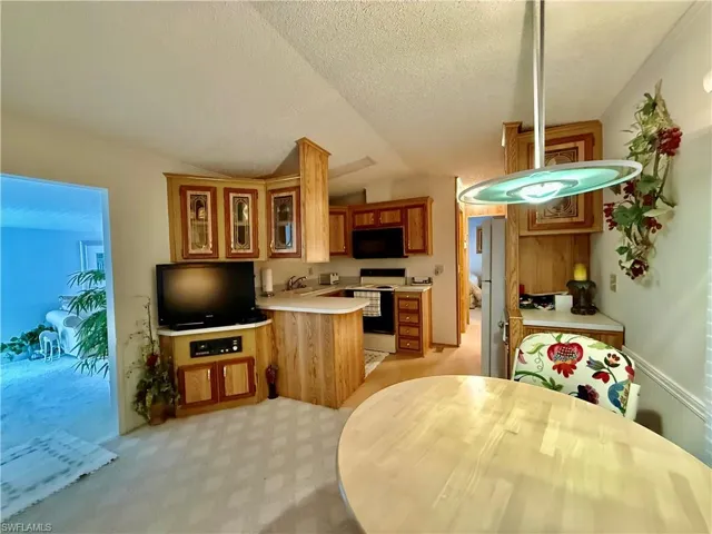 Kitchen featuring light countertops, glass fronted cabinets, electric range, a peninsula, and black microwave
