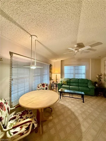 Carpeted dining area with ceiling fan and a textured ceiling