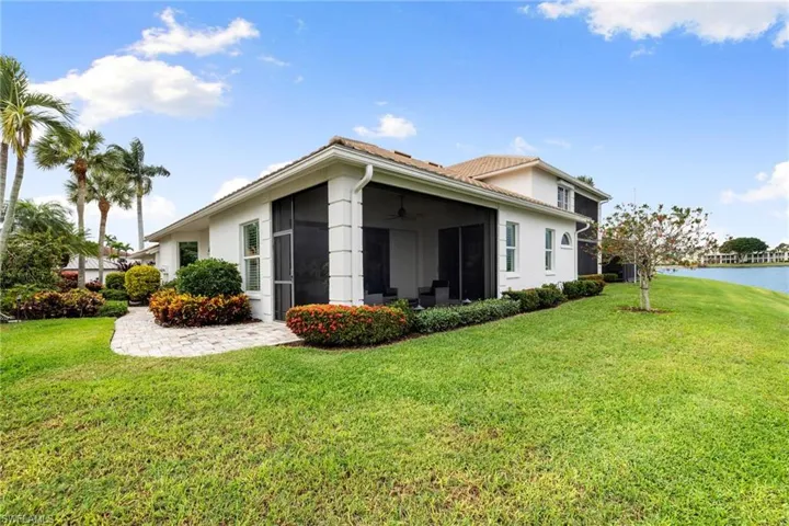 Rear view of property with a lawn, stucco siding, and ceiling fan
