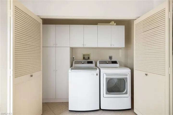 Laundry area with cabinet space, washing machine and dryer, and light tile patterned flooring