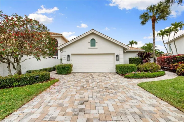 View of front facade with decorative driveway, stucco siding, a garage, and a front yard